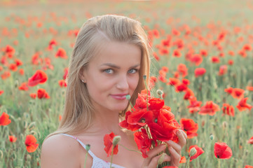 Naklejka premium Beautiful blonde girl with long hair in the poppy field