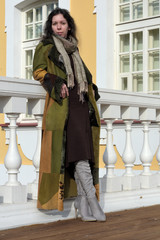 young beautiful pretty lady woman posing in a long green and brown dress gown overcoat on terrace and steps of historical palace in Oranienbaum near Saint Petersburg, Russia
