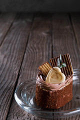   A biscuit cake is sprinkled with cocoa with chocolate cream, a heart of white chocolate, a slice of chocolate tile  and a delicious waffle on wooden background.