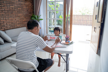 dad showing flash card with simple word to help her daughter to read