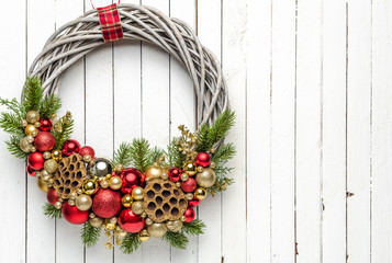 Christmas wreath on wood background with golden and red baubles and with christmas tree branches