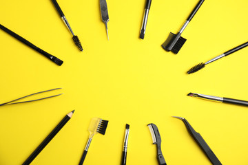 Set of professional eyebrow tools on yellow background, flat lay. Space for text