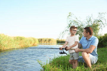 Fototapeta premium Dad and son fishing together on sunny day