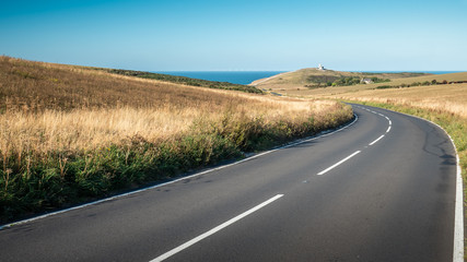 The South Downs and Belle Tout lighthouse, Sussex, England. A curved road leading to the English Channel coastline with Belle Tout lighthouse visible. - 294667623
