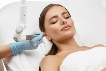 Cosmetology. Closeup Of Female Face having facial treatment in beauty salon. Cosmetic procedures in...