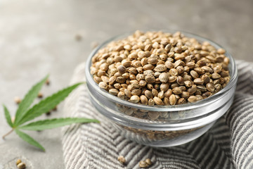 Organic hemp seeds and leaf on grey table