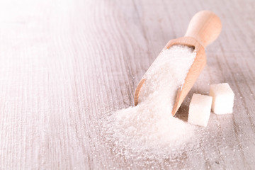 White cane sugar on a light wooden background