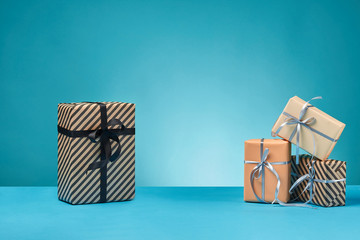 Different sizes, colorful, striped and plain paper gift boxes tied with ribbons and bows on a blue...