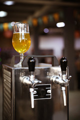 Fototapeta na wymiar Glass of refreshing beer on cooling machine in pub