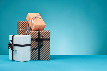 Different sizes, colorful, striped and plain paper gift boxes tied with ribbons and bows on a blue surface and background. Close-up, copy space.