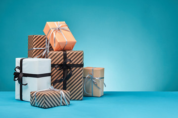 Different sizes, colorful, striped and plain paper gift boxes tied with ribbons and bows on a blue...