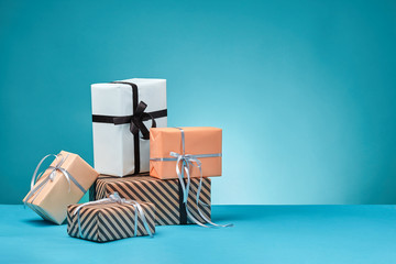 Different sizes, colorful, striped and plain paper gift boxes tied with ribbons and bows on a blue...