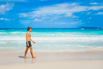 Travel vacation wallpaper - a man walking alone on white sand in sea waves of white sand paradise tropical beach at sunny day