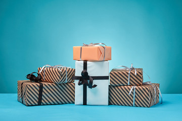 Different sizes, colorful, striped and plain paper gift boxes tied with ribbons and bows on a blue...