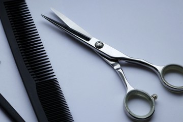 metallic scissors and black hair brush on a white background