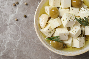 Pickled feta cheese in bowl on light brown table, top view. Space for text