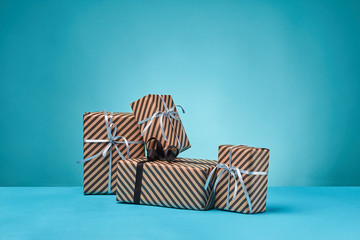 Different sizes, colorful, striped, brown paper gift boxes tied with ribbons and bows on a blue surface and background.