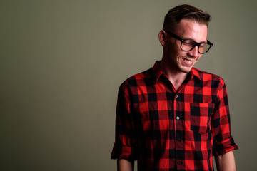 Young man wearing red checkered shirt against colored background
