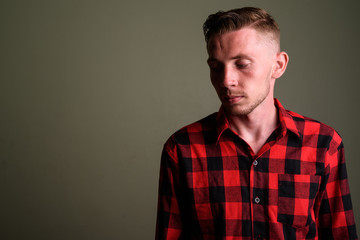 Obraz premium Young man wearing red checkered shirt against colored background