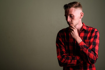 Fototapeta premium Young man wearing red checkered shirt against colored background