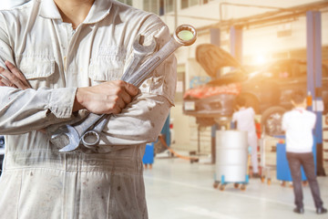 Hands of car mechanic with wrench in service center car