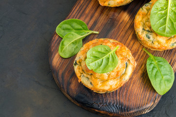 homemade cheese muffins with spinach. on dark background.