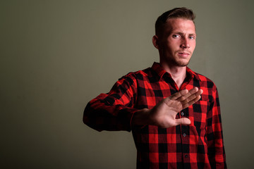 Young man wearing red checkered shirt against colored background