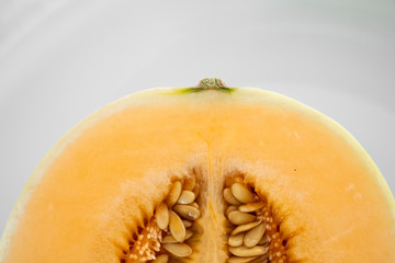 Fresh sweet orange melon on the white plate as a background with a selective focusing. Useful and vitamin-rich food. Vegeterian.
