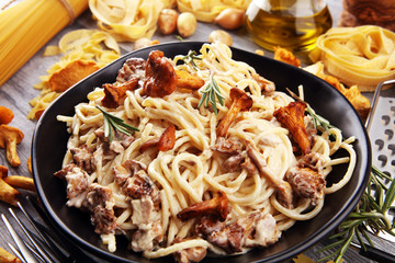 pasta with organic chanterelles. portion of spaghetti pasta with fried chanterelles in a creamy garlic sauce with cheese on a table