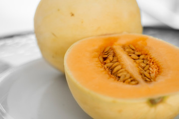 Fresh sweet orange melon on the white plate as a background with a selective focusing. Useful and vitamin-rich food. Vegeterian.