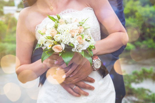 Close-up of newlywed husband embracing wife. Young bride holding wedding bouquet. Happy family life, romance, marriage