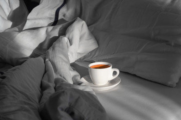 Morning coffee in bed. Cup of coffee on the bed in the room with a lot of natural sunlight. Enjoying the little things. Morning concept