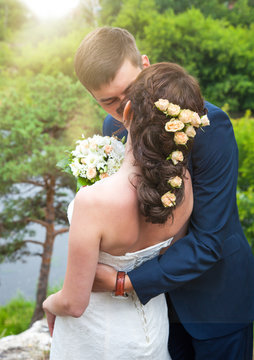 Rear view of happy newlywed couple kissing outdoors. Married couple at wedding vacation. Wedding, marriage, romance
