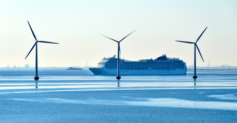 A large cruise ship passes offshore wind turbines near the Oresund Bridge between Denmark and...