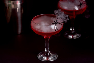 Two Halloween bloody cocktails with spidera in halloween bloody cocktail with spider