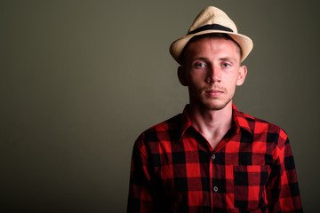 Young tourist man wearing hat and red checkered shirt against co