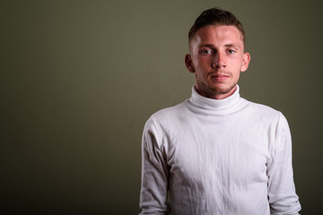 Obraz premium Young man wearing white turtleneck sweater against colored backg