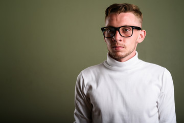 Obraz premium Young man wearing white turtleneck sweater against colored backg