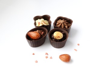 four chocolate candies with nuts on a white background