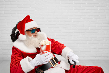 Santa Claus sitting in chair with popcorn and TV zapper