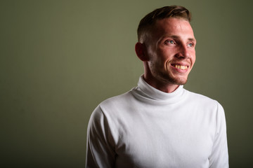 Obraz premium Young man wearing white turtleneck sweater against colored backg