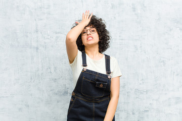young pretty afro woman raising palm to forehead thinking oops, after making a stupid mistake or...