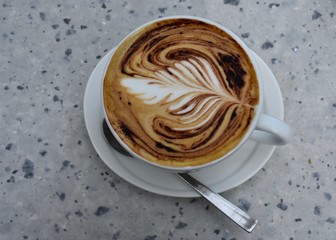  A cup of cappuccino on a granite table with a beautiful decorative foam layer