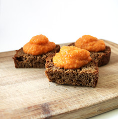 Toasted rye bread with vegetable caviar puree on a wooden cutting desk rustic style background