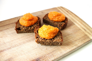 Toasted rye bread with vegetable caviar puree on a wooden cutting desk rustic style background