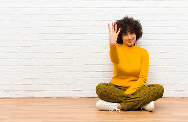 young pretty afro woman smiling and looking friendly, showing number four or fourth with hand...
