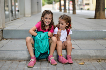 Two little girls having a snack in the afternoon after school