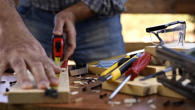 Adult carpenter craftsman takes the measure and with the carpenter's square trace the cutting line on a wooden table. Construction industry, housework do it yourself. Footage.