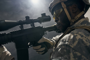 Close up of American soldier keeping sight on modern gun.