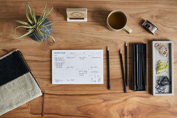 Overhead still life of a weekly calendar on a wooden desk
